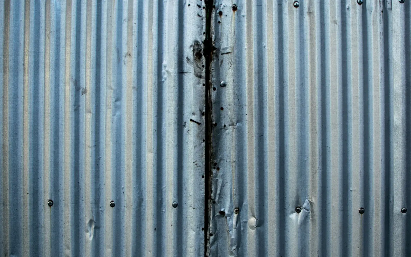 Corrugated metal panels with worn laps and streaked fasteners