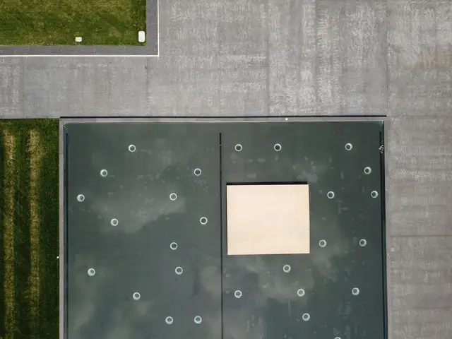 Aerial view of a flat membrane roof with drains and a hatch