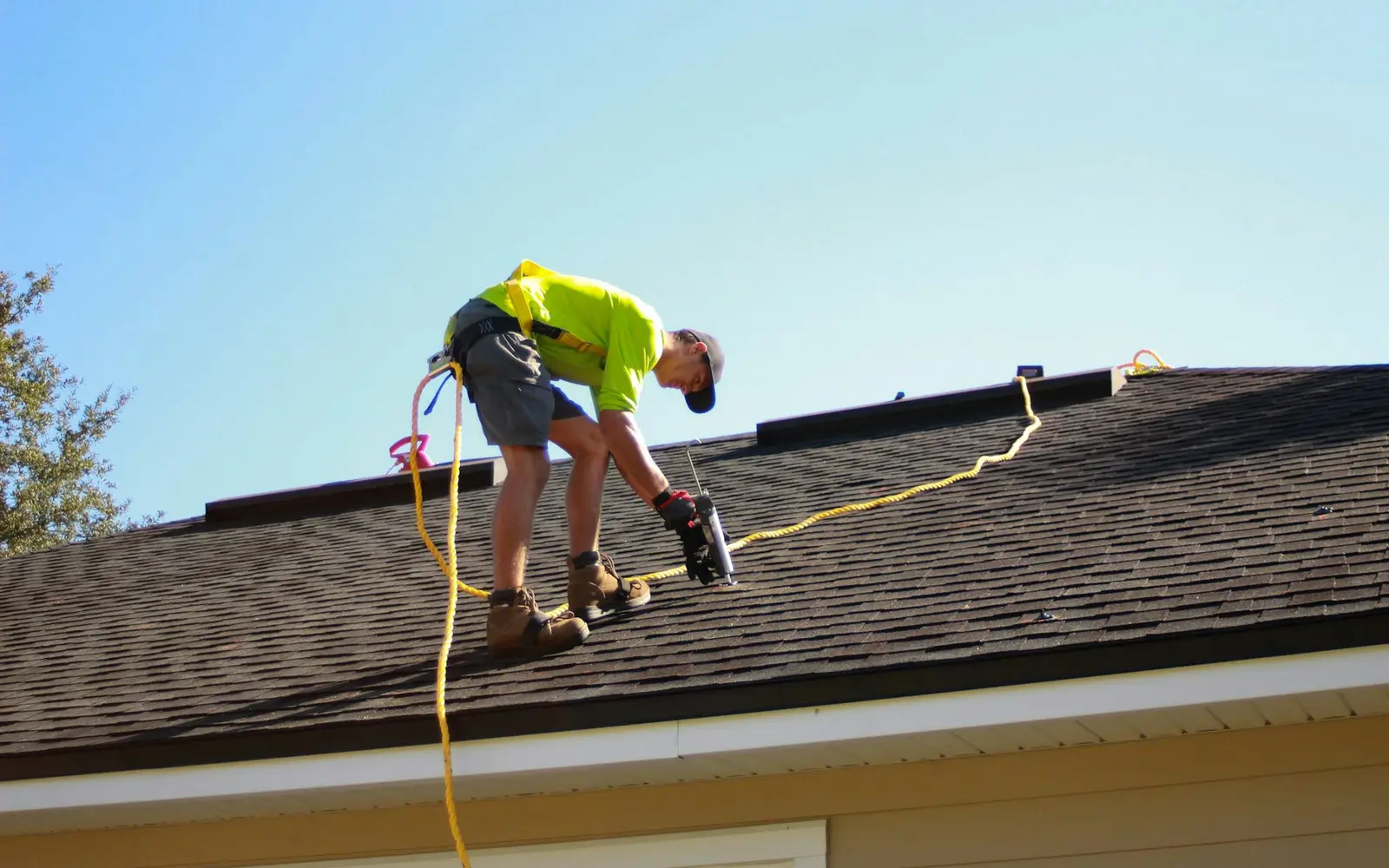 Roofer checking a shingle roof while roped in