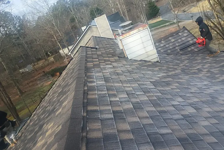 Roofer laying new architectural shingles along a roof slope