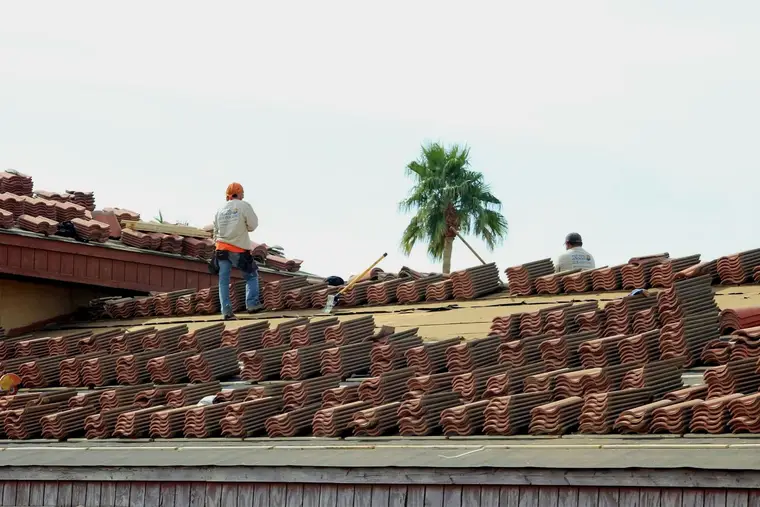 Roofers on a roof with stacks of clay tile ready to lay